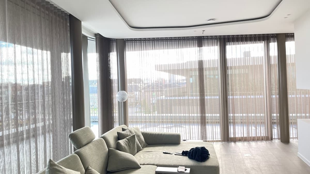 Doorschijnende verticale lamellen in een woonkamer met hoekzetel - Sin-tex gordijnen en raamdecoratie, Heusden-Zolder