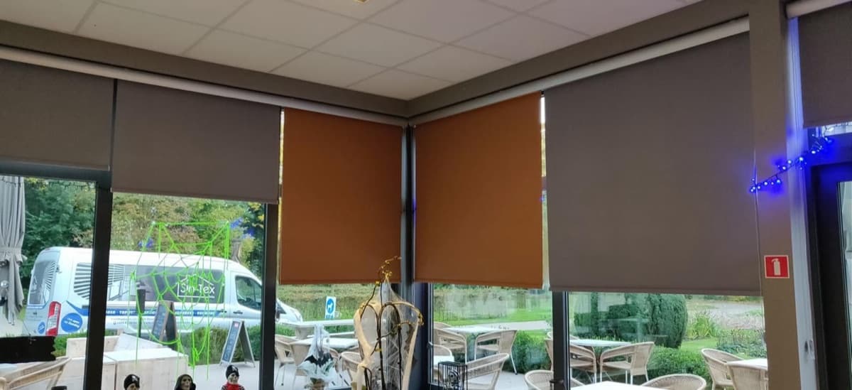 Grijze en oranje rolgordijnen in een horecazaak - Sin-tex gordijnen en raamdecoratie, Heusden-Zolder