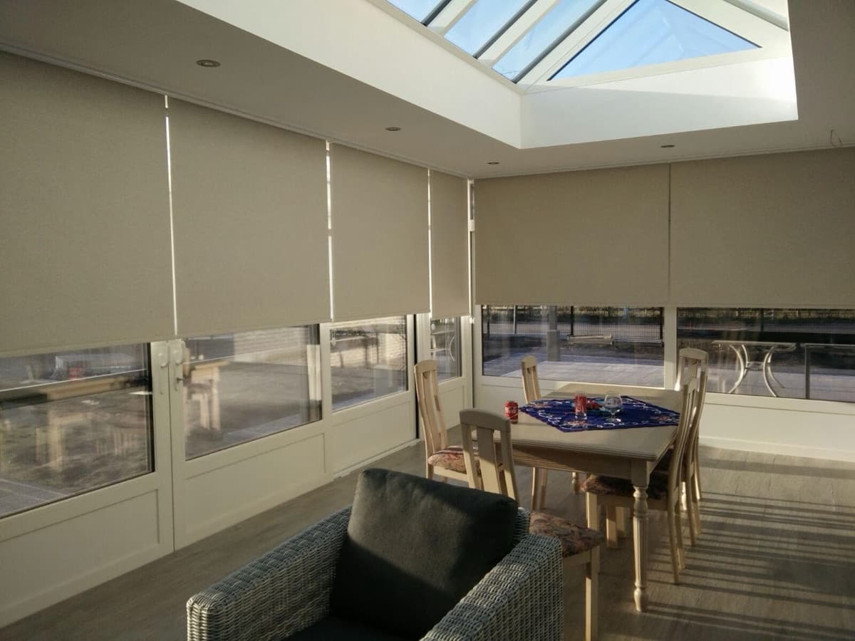 Beige rolgordijnen in een veranda met lichtstraat - Sin-tex gordijnen en raamdecoratie, Heusden-Zolder