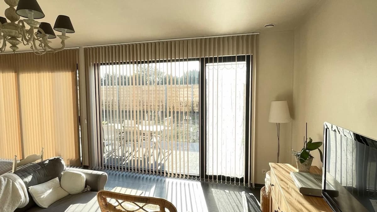 Okergele verticale lamellen in een woonkamer met schuifraam - Sin-tex gordijnen en raamdecoratie, Heusden-Zolder