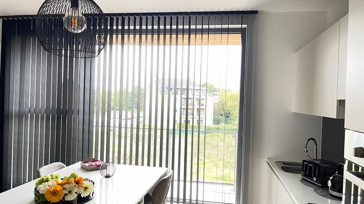 Donkergrijze verticale lamellen bij de eettafel in een keuken - Sin-tex gordijnen en raamdecoratie, Heusden-Zolder