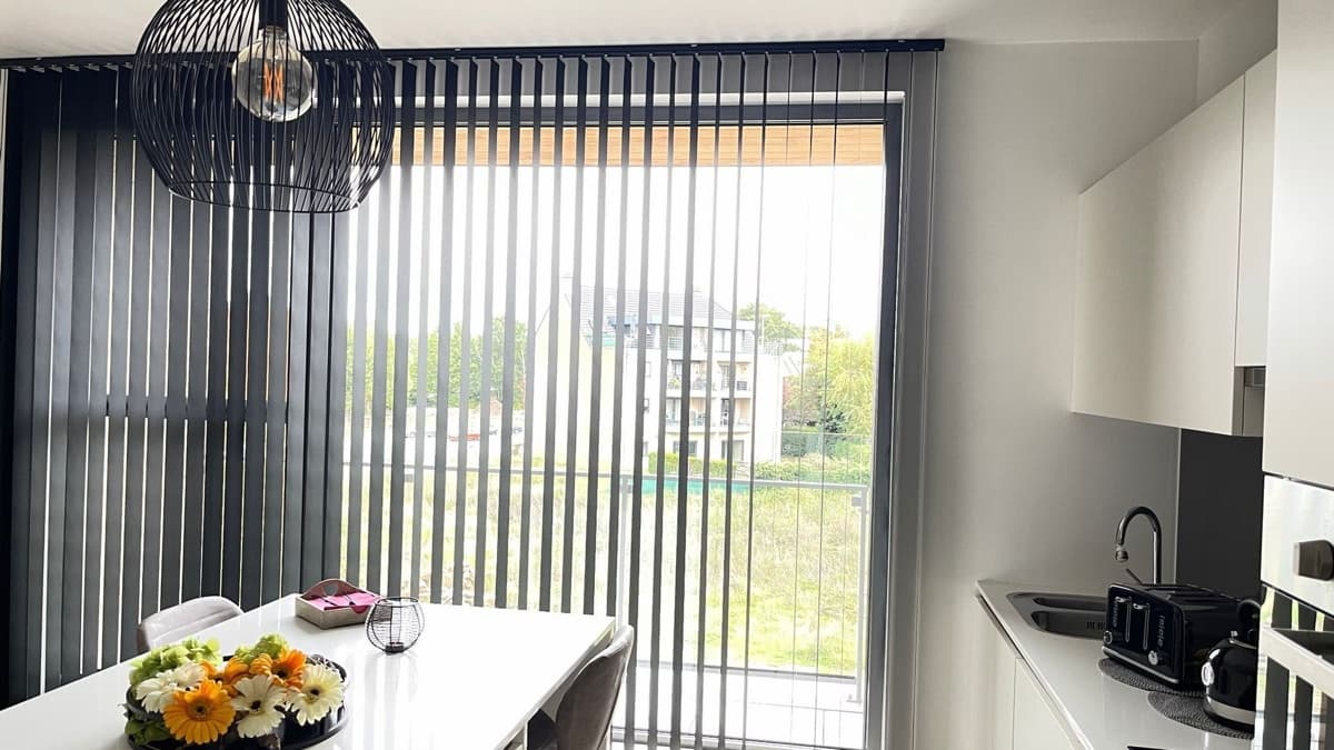 Donkergrijze verticale lamellen in een keuken met zicht op het terras - Sin-tex gordijnen en raamdecoratie, Heusden-Zolder