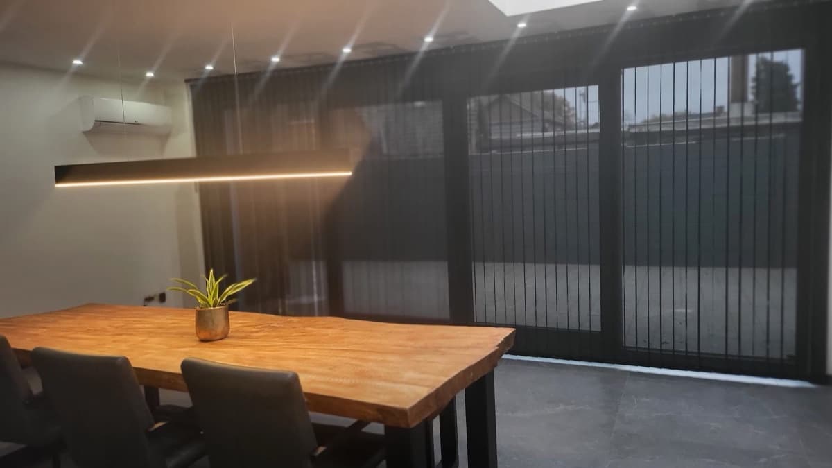 Donkere stoffen lamellen langs een glaswand met eettafel - Sin-tex gordijnen en raamdecoratie, Heusden-Zolder